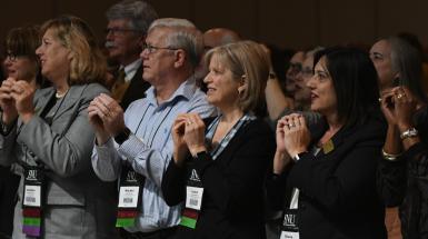 board members standing with hands cupped at general conference session