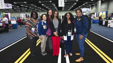A group of 6 African-American woman standing and smiling in the CEC 2020 Expo Hall