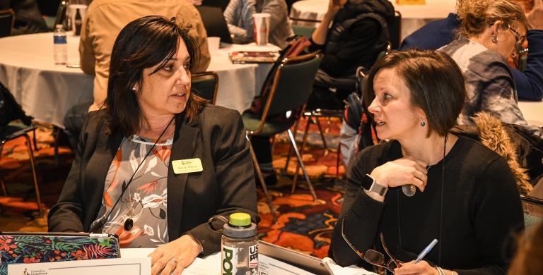 Two women discussing at a table at conference